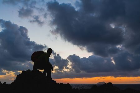 Man hiker sitting accomplish silhouette backpacker, looking at inspirational ocean island landscape, freedom concept. Fitness and healthy lifestyle outdoors at beach Crete, Greece.の写真素材