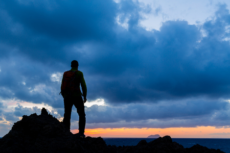 Hiking or trail running accomplish silhouette hiker backpacker, man and success in inspirational sunset landscape. Fitness and healthy lifestyle outdoors in summer nature on Crete, Greece.の写真素材