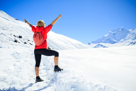 Young happy woman hiker with arms hands outstretched in winter mountains. Climbing inspiration and motivation, beautiful landscape with business concept. Fitness healthy lifestyle on snow in Himalayas, trekking Nepal.の写真素材
