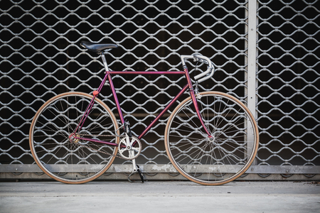 Fixed gear bike. Road bicycle on city street. Urban industrial cycling, garage door or gate on city scene bike closeup details, vintage old retro bike, cycling or ecology commuting. Industrial concept.の写真素材