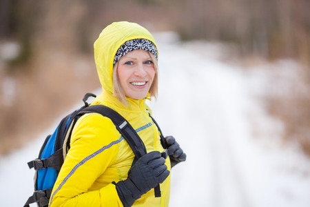 Woman walking and hiking in white winter forest. Recreation and healthy lifestyle outdoors in nature. Beauty blond looking at camera on sunset. Inspirational winter landscape.の写真素材