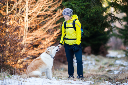 Woman hiking in white winter forest woods with akita dog. Recreation fitness and healthy lifestyle outdoors in nature. Motivation and inspirational winter landscape.の写真素材