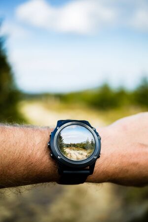 Wearable technology, man taking photo with smartwatch camera in mountains. Smart watch photography with camera app application in beautiful inspirational landscape. Modern electronics in use.の写真素材