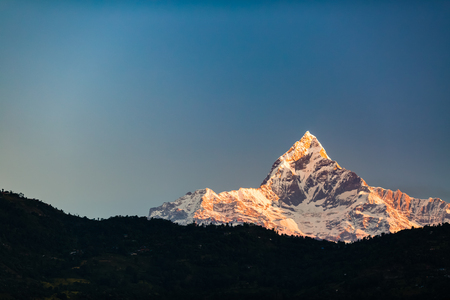 Mountain inspirational beautiful sunset landscape in Himalaya Mountains. Himalayas peak Machhapuchhare 6993m ASL over blue sunny sky, Nepalの写真素材