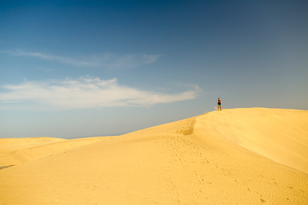 Young woman running on beautiful inspirational desert dunes on sunny summer day. Female runner training and working out, jogging and exercising outdoors in nature, Gran Canaria, Canary Islands Spain.の写真素材