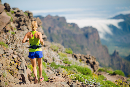 Young woman running in mountains on sunny summer day. Beauty female runner jogging and exercising outdoors in inspirational landscape, rocky trail footpath on La Palma, Canary Islands.の写真素材