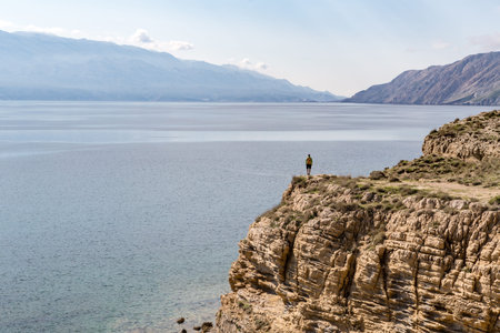 Hiking man, climber or trail runner in mountains, inspirational landscape. Motivated hiker with backpack looking at beautiful view. Trekking, travel and tourism concept. Fitness and healthy lifestyle.の写真素材