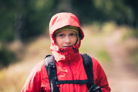 Woman hiking in autumn woods, portrait on forest trail. Recreation and healthy lifestyle outdoors, fall forest in mountains, inspirational nature. Fitness and trekking and activity concept.の写真素材