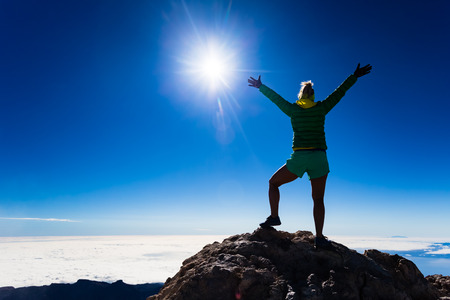 Woman successful hiking climbing silhouette in mountains, motivation and inspiration landscape on island and ocean. Hiker with arms up outstretched on top looking at beautiful view on Tenerfie Spain.の写真素材