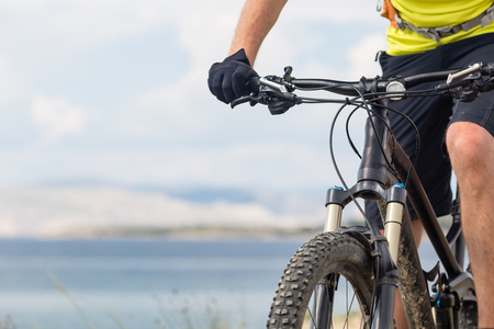 Mountain biker riding on bike at the sea and summer mountains. Man rider cycling MTB on country road or single track. Sport fitness motivation, inspiration in beautiful inspirational landscape.の写真素材