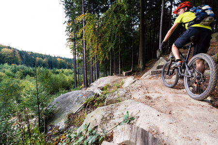 Mountain biker riding on bike in autumn inspirational mountains landscape. Looking at beautiful fall woods. Man cycling MTB on enduro trail track. Sport fitness motivation and inspiration.の写真素材