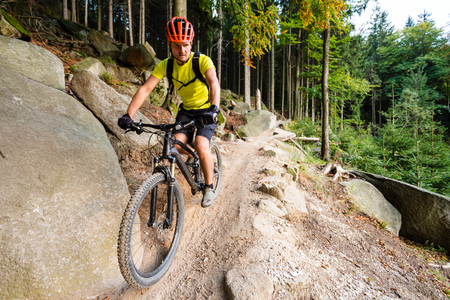 Mountain biker riding on bike in autumn inspirational mountains landscape. Man cycling MTB on enduro trail track. Sport fitness motivation and inspiration.の写真素材