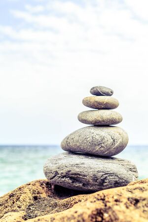 Stones balance and wellness retro spa concept, inspiration, zen-like and well being tranquil composition. Close-up of white pebbles stack over blue seaの写真素材