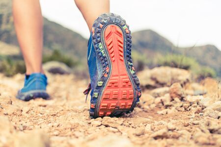 Hiking or running woman in beautiful mountains inspirational landscape. Sole of sports shoe and legs on rock trail. Hiker trekking or walking of footpath. Healthy fitness lifestyle outdoors.の写真素材