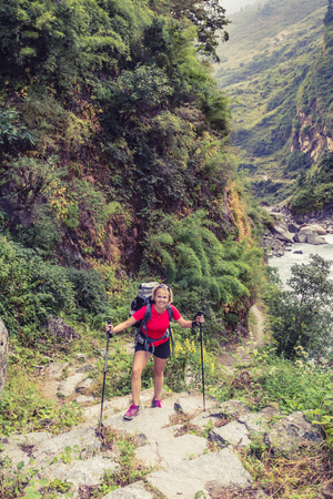 Female backpacker climbing with backpack in Himalayas, Nepal. Trekking and hiking with backpack in high mountains. Annapurna Himal Range on Annapurna Circuit Trek. Autumn season in Nepal, Asia.の写真素材