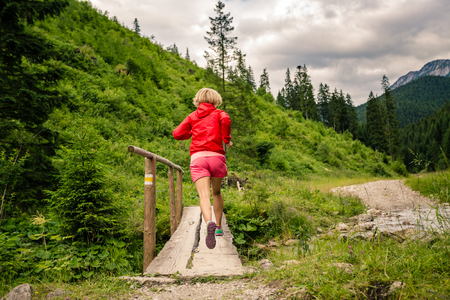 Young woman running in mountains on summer sunny dayの写真素材