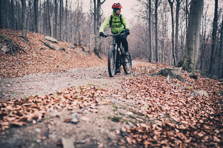 Mountain biker cycling on trail in woods. Mountains in winter or autumn landscape forest. Man cycling MTB on rural country road. Sport fitness motivation and inspiration.の写真素材