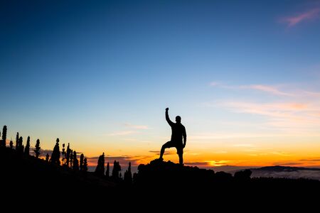 Man celebrating sunset in mountains with arms outstretched. Trail runner, hiker or climber with hands raised reached a goal on top of a mountain, enjoying inspirational landscape on rocky trail Tenerife, Canary Islandsの写真素材