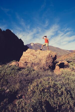 Man celebrating beautiful inspiring view in mountains. Hiker or climber looking at inspirational landscape on rocky trail on Tenerife, Canary Islands.の写真素材