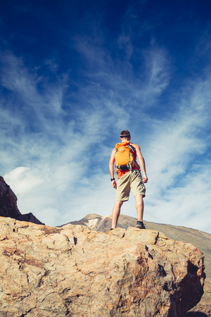Man celebrating beautiful inspiring view in mountains. Hiker or climber looking at inspirational landscape on rocky trail on Tenerife, Canary Islands.の写真素材