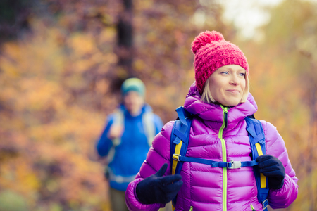 Happy couple hikers camping in beautiful yellow autumn forest and mountains. Young partnership teamwork, man and woman walking with backpacks, healthy lifestyle adventure, camping on hiking trip.の写真素材