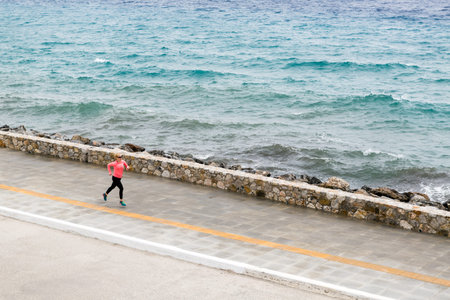 Woman running on city street at seaside. Young athlete  training and doing workout outdoors in urban scene. Sport and fitness training inspiration and motivation. Vintage tone.の写真素材