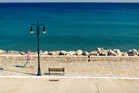 Woman jogging on city street at seaside. Young athlete  training running and doing workout outdoors...