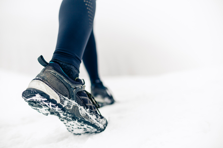 Hiking or walking shoes on snow, winter mountains.  People power walking on snow, white winter day. Female hiker on winter adventure. Sport, fitness inspiration and motivation.の写真素材