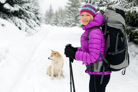 Woman hiking in white winter forest woods with akita dog. Recreation fitness and healthy lifestyle outdoors in nature. Motivation and inspirational winter landscape.の写真素材