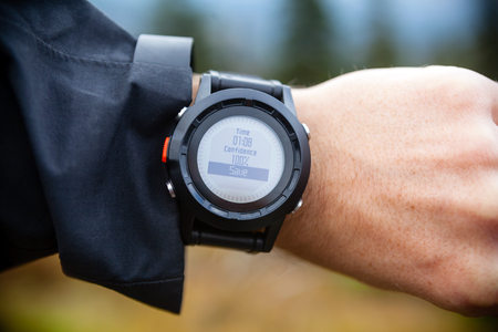 Hiker on mountain trail looking at sportwatch, checking direction on electronic compass, hiking and navigation.の写真素材