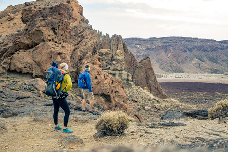 Family hiking with baby boy travelling in backpack. Hiking adventure with child on autumn family trip in mountains. Vacations journey with infant carried on back, weekend travel in Tenerife, Spain.の写真素材