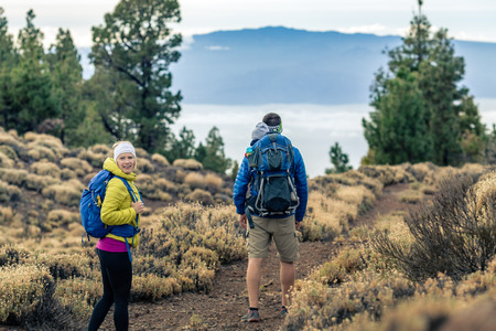 Couple hiking with baby boy travelling in backpack. Hikers family, adventure with child on autumn family trip in mountains. Vacations with infant carried on back, weekend travel in Tenerife, Spain.の写真素材
