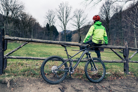 Mountain biker riding on trail in woods. Mountains in winter or autumn landscape forest. Man cycling MTB on rural country road. Sport fitness motivation and inspiration.の写真素材