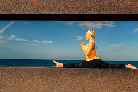 Woman meditating in yoga pose, ocean view, beach and wooden sidewalk. Motivation and inspirational summer sea landscape. Healthy lifestyle outdoors in nature concept.の写真素材