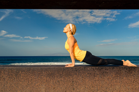 Woman meditating in yoga pose, ocean view, beach and wooden sidewalk. Motivation and inspirational summer sea landscape. Healthy lifestyle outdoors in nature concept.の写真素材