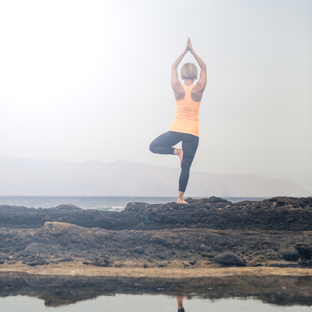 Woman meditating in yoga pose, ocean view, beach and rocks. Motivation and inspirational summer sea landscape, healthy lifestyle concept.の写真素材