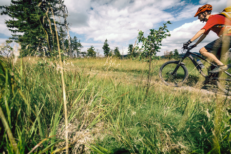 Mountain biking man riding on bike in summer inspirational landscape. Bikepacking, cycling on enduro trail. Sport fitness motivation and inspiration. MTB Rider mountain biker in summer woods.の写真素材