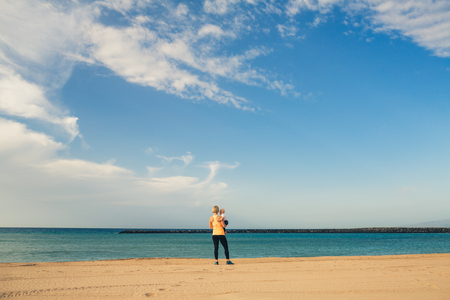 Mother with baby boy enjoy sunrise on a beach. Walking and relaxing woman holding baby boy toddler. Beautiful inspirational beach and ocean landscape.の写真素材