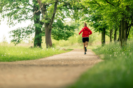 Running woman, enjoying summer day in park. Endurance training, jogging or power walking female athlete, physical activity concept outdoors.の写真素材