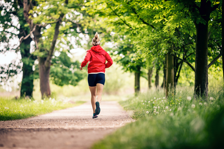 Running woman, enjoying summer day in park. Endurance training, jogging or power walking female athlete, physical activity concept outdoors.の写真素材
