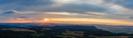 Sunset panorama, landscape with green forest and beautiful inspirational Table Mountains. Evening sky with orange sun and clouds, Poland Europe.の写真素材