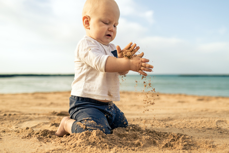 Baby boy playing on a beach. Toddler sitting and walking on sand. Beautiful inspirational beach and ocean landscape.の写真素材