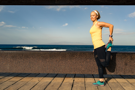 Woman runner stretching at the seaside on sunny summer day. Fitness girl running and exercising on a coastline in  Tenerife, Spainの写真素材