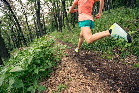 Young woman running in green forest. Endurance sport training. Female trail runner cross country running. Sport and fitness concept outdoors in nature.の写真素材