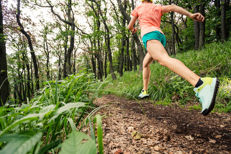 Young woman running in green forest. Endurance sport training. Female trail runner cross country running. Sport and fitness concept outdoors in nature.の写真素材