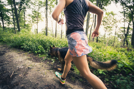 Trail running athletic woman in green forest, sports inspiration and motivation. Female trail runner cross country running. Fitness concept outdoors in nature.の写真素材
