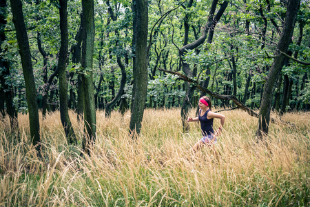 Trail running athletic woman in green forest, sports inspiration and motivation. Female trail runner cross country running. Fitness concept outdoors in nature.の写真素材