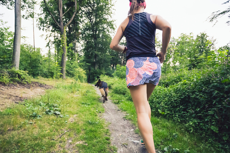 Trail running athletic woman in green forest, sports inspiration and motivation. Female trail runner cross country running. Fitness concept outdoors in nature.の写真素材