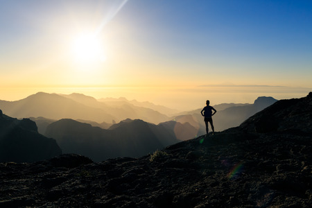 Woman hiking silhouette in mountains, sunset and ocean. Female hiker looking at beautiful inspiring view, sunset inspirational landscape.の写真素材
