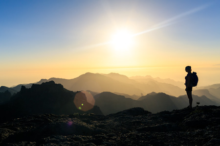 Woman hiking silhouette in mountains, sunset and ocean. Female hiker looking at beautiful inspiring view, sunset inspirational landscape.の写真素材